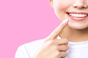 Perfect healthy teeth smile of a young woman. Teeth whitening. Dental clinic patient. Image symbolizes oral care dentistry, stomatology. Pink Background.